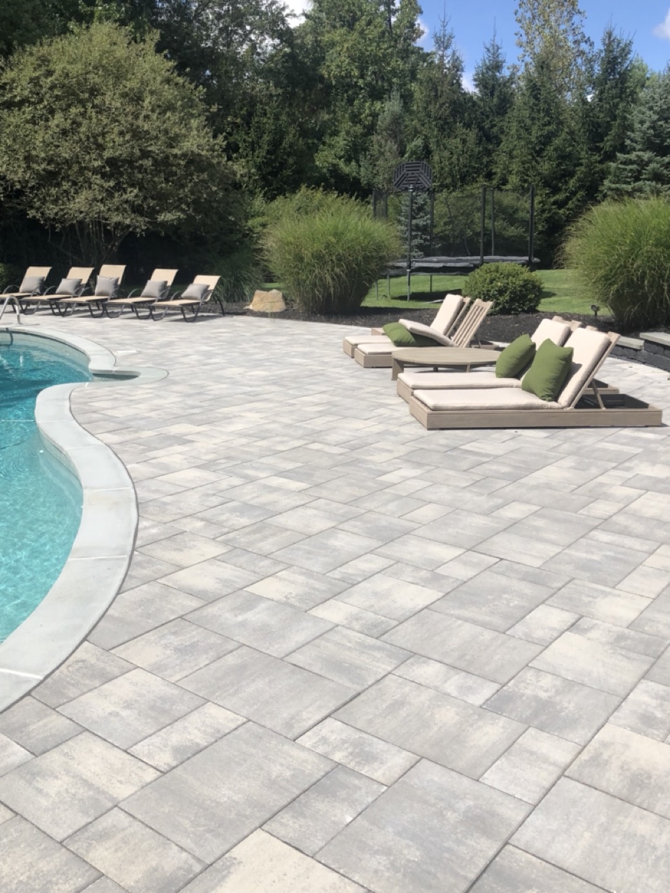 Paver pool surround with cushioned lounge chairs and ornamental grass planting beds — Alpine