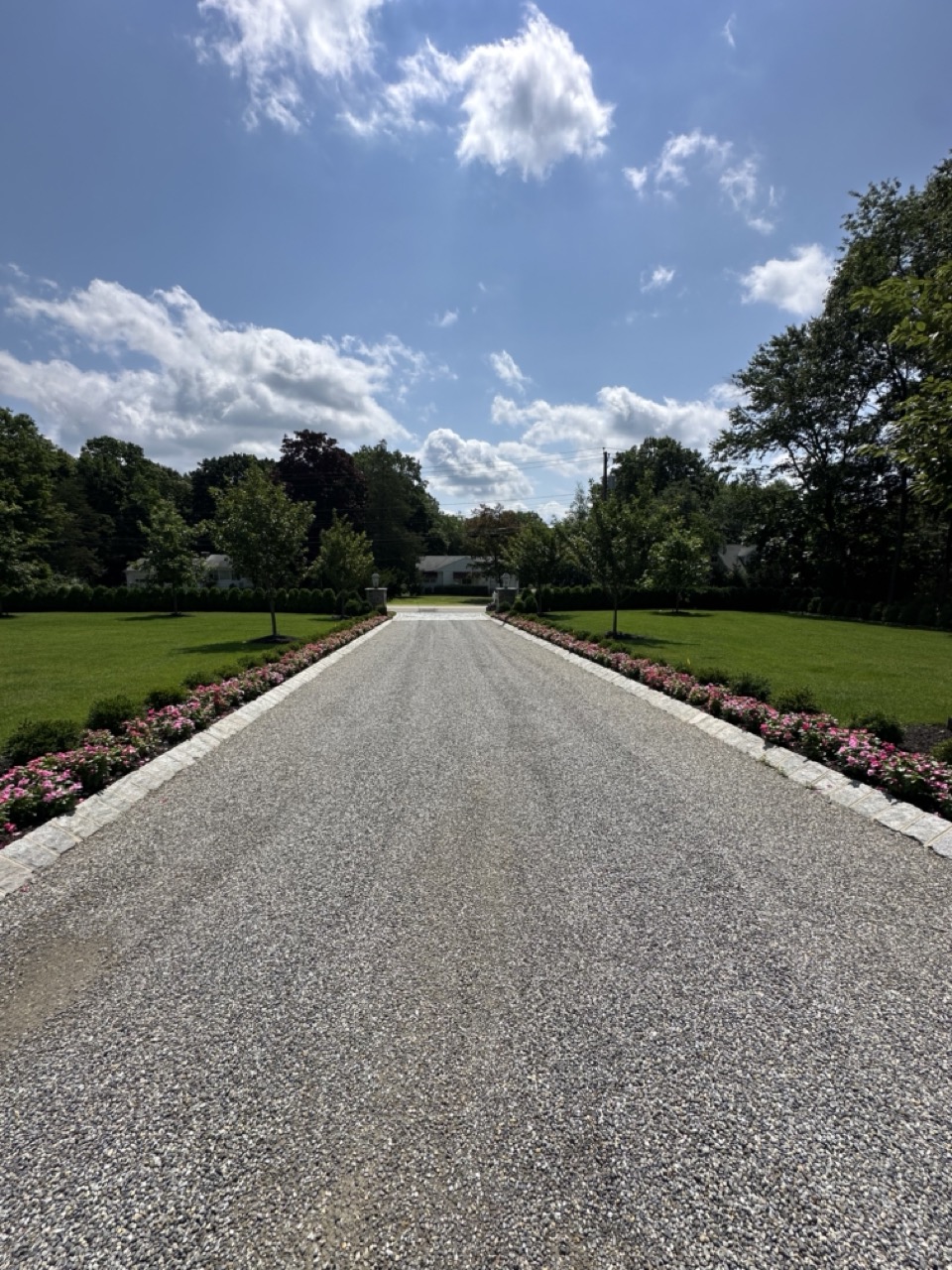 Long gravel driveway with granite border and flower beds