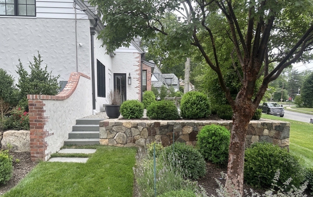 Stone retaining wall with brick post, boxwood and lavender plantings framing the front entrance — Ho-Ho-Kus