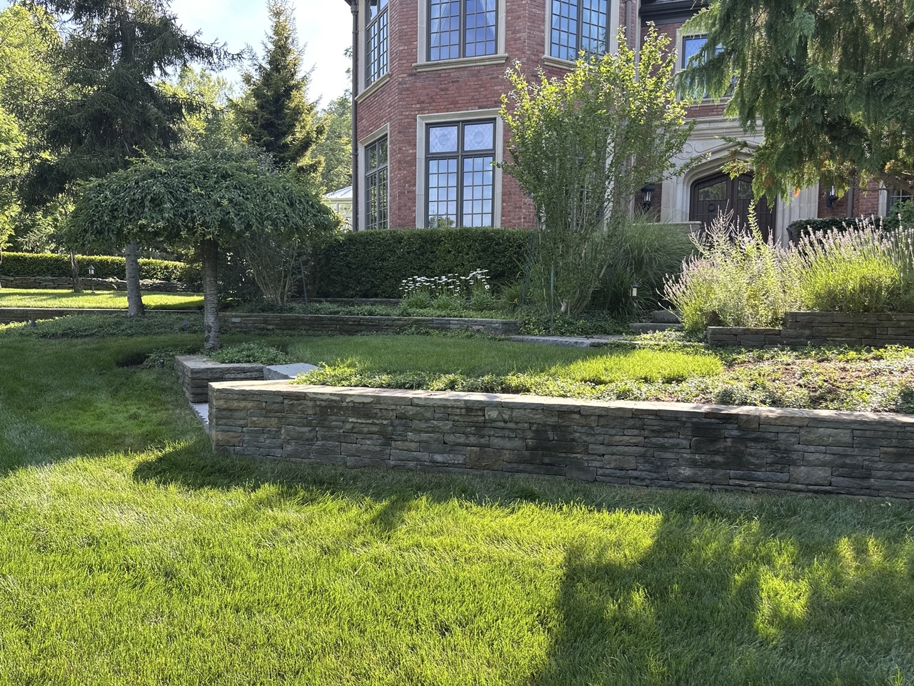 Tiered dry-stack retaining walls with lavender and perennial beds along the estate foundation