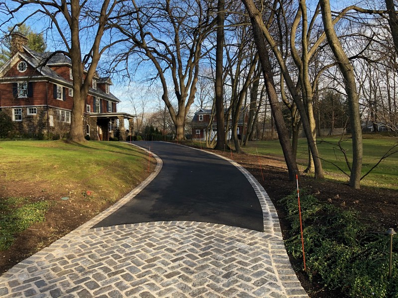 Long winding asphalt driveway with Belgian block soldier-course border