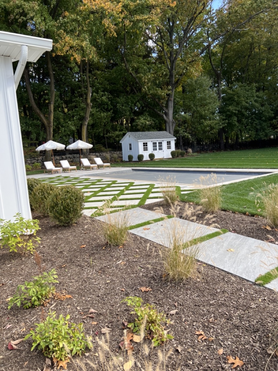 Stepping stone path through ornamental grass planting bed with pool and pool house beyond — Wyckoff