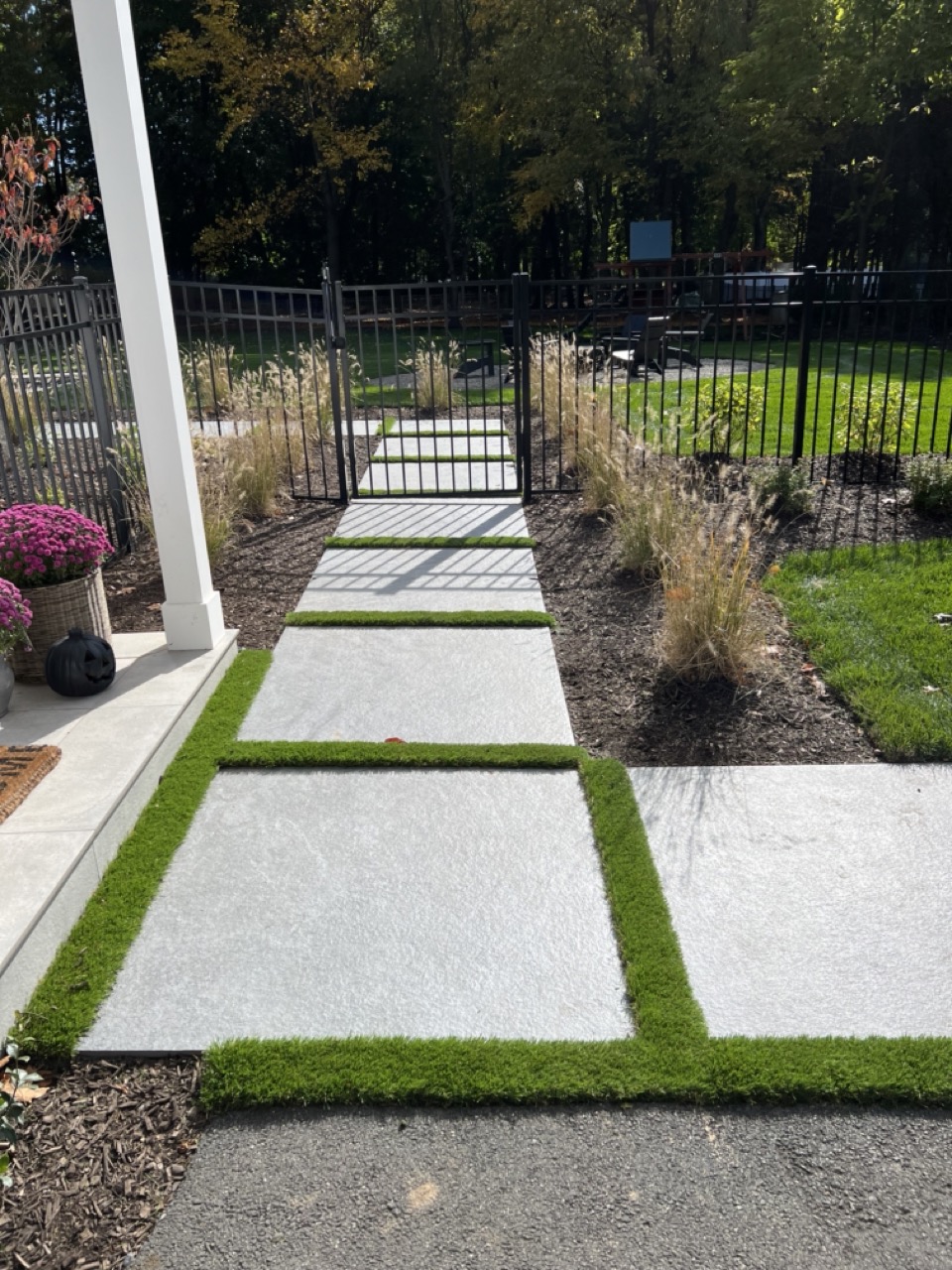 Large-format bluestone stepping path with turf joints through iron gate to pool area — Wyckoff